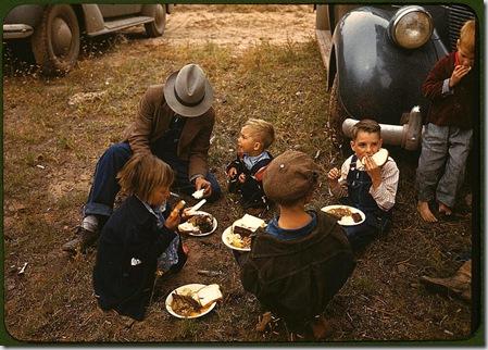 Homesteader and his children eating barbeque at the New Mexico Fair. Pie Town, New Mexico, October 1940. Reproduction from color slide. Photo by Russell Lee. Prints and Photographs Division, Library of Congress