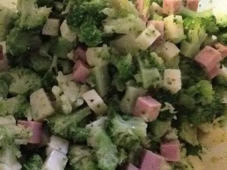 Riducete i broccoli a tocchetti piccoli e aggiungete il prosciutto e il formaggio a cubetti. Salate moderatamente e pepate a piacere, unite tre cucchiai di olio extravergine d'oliva e mescolate bene.