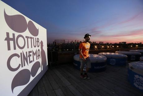A man walks past the screen at a Hot Tub cinema event on a warehouse roof in Hackney, east London