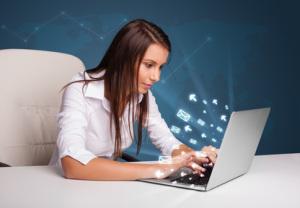 Young lady sitting at dest and typing on laptop with message ico