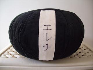 L'immagine rappresenta il mio zafu, in camera mia posizionato su un cesto bianco. E' tutto nero e ha la fascetta bianca con su scritto il mio nome in giapponese.