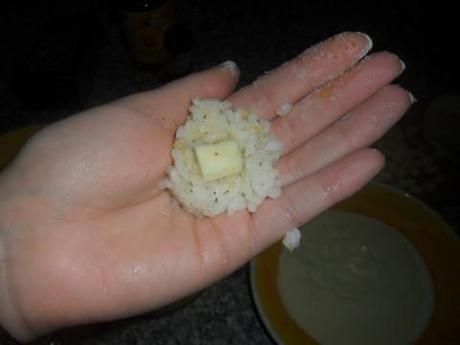 Prendete una piccola porzione di riso, schiacciatela al centro e inserite un pezzetto di provola. Chiudete aggiungendo un altro pò di riso e compattate l'arancino con le mani.