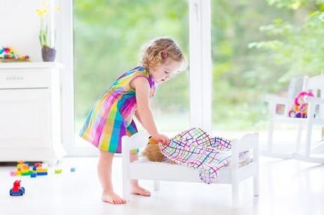 Happy beautiful curly toddler girl in a pink dress playing with