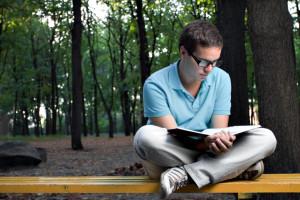 young man reading book in the park