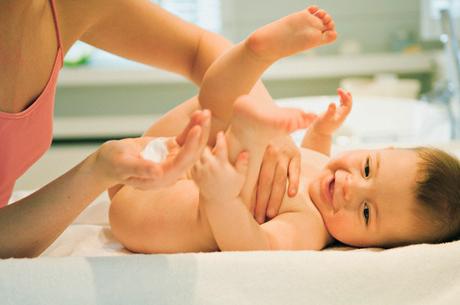 Mother and naked baby, milky cleanser in her hand