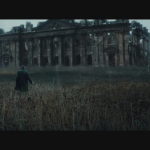 08 - Qualcuno cammina in un campo dinnanzi ad una magione in rovina. Sembra la Wayne Manor e il personaggio dovrebbe essere Alfred (Jeremy Irons)