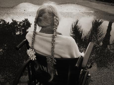 Madje Steber siede nella sua sedia a rotella durante il un giro pomeridiano a seguito di un temporale estivo a Hollywood, Florida. Davanti a lei c'è una pozza d'acqua, quasi senza riflessi se non per qualche fronta di una palma, che richiama gli spazi vuoti che abitano la sua mente per via della perdita di memoria.