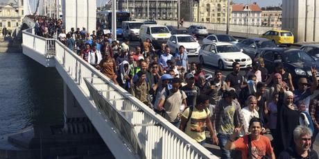Hundreds of migrants cross the river Danube in Budapest, Friday Sept, 4, 2015, after they decided to walk toward Austria. Thousands have been camped out at Budapest's Keleti train station for days, before they decided to try and reach their destination on foot. (AP Photo/Bela Szandelszky)