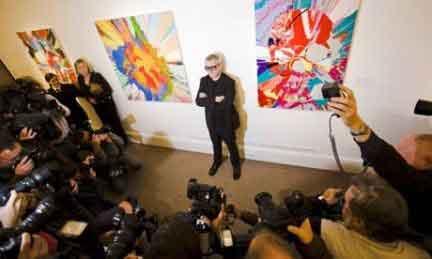 Damien Hirst in posa davanti ai fotografi in mezzo a due sue opere da Sothebys