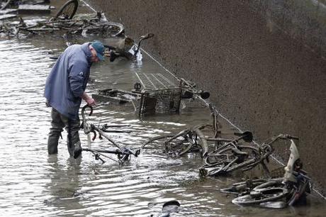 A worker wades in the water as he inspects abandoned bicycles during the draining of the Canal Saint-Martin in Paris