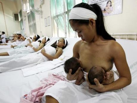 A young mother breastfeeds her twins at a ward of a state-owned Fabella maternity hospital in Manila