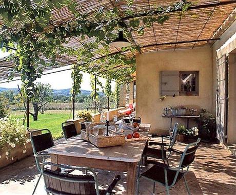 La terrasse a été couverte de béton teinté sur lequel un calepinage de galets avec un élégant quadrillage. La treille recouverte de cannisses qui tamisent la lumière, sur la table chiné dans une brocante verres, panier, gobe-mouche et set (Comptoir de famille)