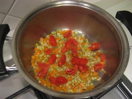 In un'ampia pentola far rosolare leggermente la cipolla tagliata a pezzettini nell'olio, aggiungere le carote e il sedano lavati e tagliati a pezzetti piccoli. Far cuocere per circa 5 minuti e aggiungere i pomodorini tagliati in 4 parti. Cuocere per altri 2-3 minuti.