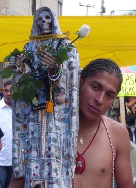 La Santa Muerte a Bucanero di Radio Popolare Roma Devoto Santa Muerte con Statua in mano