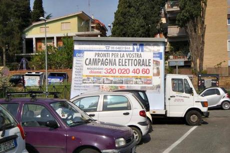 SIAMO PRONTI PER LA VOSTRA CAMPAGNA ELETTORALE! UN BEL FACCIONE CON SORRISO EBETE E SULLO SFONDO UNA PROCESSIONE DI CASSONETTI DELLA MUNNIZZA. MANCO CETTO LAQUALUNQUE AVREBBE OSATO TANTO...