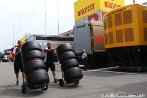 Mechanics wheeling tyres through the paddock