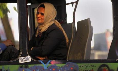 A woman wearing a traditional head-scarf sits inside a damaged bus used by anti-government protesters as a barricade in Istanbul's Taksim square