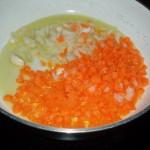 In un'altra padella, preparare un soffritto con mezza cipolla e una carota tagliata a dadini piccoli e uno spicchio d'aglio.