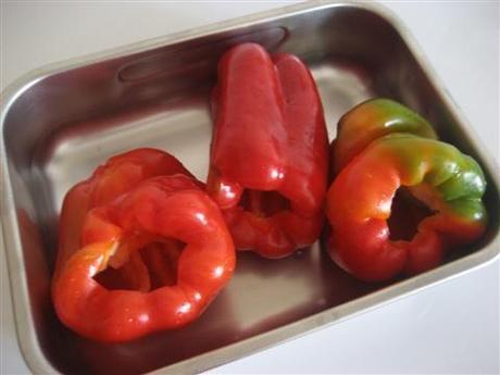 Eliminare il torsolo, sciacquare sotto acqua corrente sia l'interno che l'esterno in modo da eliminare una parte dei semini. Asciugare con uno strofinaccio pulito i peperoni e disporli in una teglia.