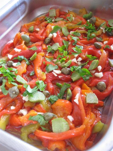 In una teglia aggiungere i peperoni, l'aglio tagliato a pezzettini, le olive snocciolate e tagliate a pezzetti, i capperi, il prezzemolo e l'olio. Cuocere a 180° per 20 minuti.