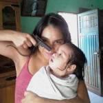 Foto choc: Madre sorridente punta pistola contro figlio neonato
