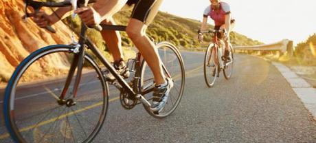 Man riding bicycle with woman trailing behind