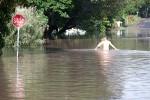 Kasper Skou and Aron Banks wade through flood waters to their home in the Brisbane suburb of Fairfield.