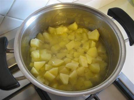 aggiungere le patate precedentemente sbucciate, lavate e tagliate a dadini. Cuocere a fuoco moderato per 2 minuti e con coperchio chiuso. Aggiungere dell'acqua tiepida e continuare la cottura fin quando le patate saranno quasi cotte.