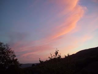 Foto delle colline all'alba con sopra il cielo pennellato di nuvole rosa