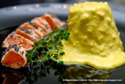 Filetto di salmone leggermente arrostito in crosta di semi di papavero e ricotta fresca glassata con crema di zenzero e curcuma al profumo di timo limone