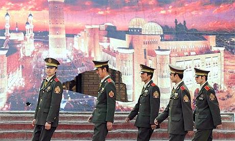 Security guards walk in front of a mural of a mosque in the city of Urumqi in China's Xinjiang province