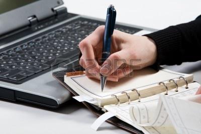 3707930-close-up-of-female-mano-che-regge-la-penna-e-prendere-appunti-in-notebook-con-computer-portatile-a-s