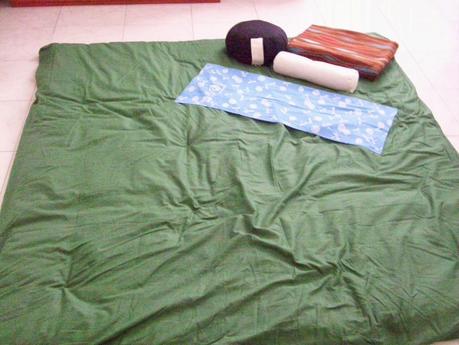 L'immagine rappresenta il mio futon verde con sopra zafu, makura, tenugui e plaid. Il futon è stropicciato perchè era appena stato fatto un trattamento.