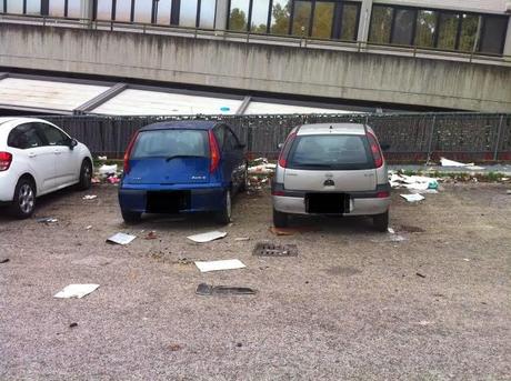 Via Sbricoli al Portuense. Lo stato di un parcheggio vicino a: un ristorante, una sede Asl, un condominio di tre palazzine e vari uffici