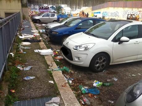 Via Sbricoli al Portuense. Lo stato di un parcheggio vicino a: un ristorante, una sede Asl, un condominio di tre palazzine e vari uffici