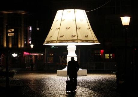 A man walks past a giant lamp placed on Lilla Torg square in Malmo
