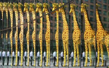 A man walking past a giant giraffe made