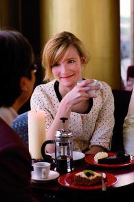 Young woman holding a coffee cup and gently smiling at man.