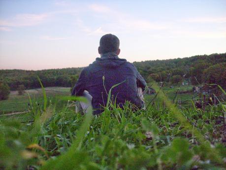 Foto che mi ritrae seduto di spalle sull'erba con un panorama verdeggiante di fronte