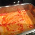 Adagiare uno strato di lasagne, il sugo e una manciata di formaggio grattugiato.