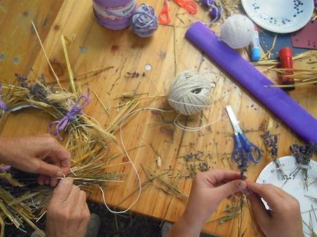 Piccole e grandi mani al lavoro con paglia di segale, lavanda e...