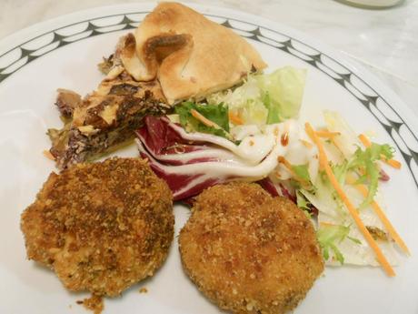 Le polpette sono nel piatto servite con l'insalata e una fetta di tortino di verdure