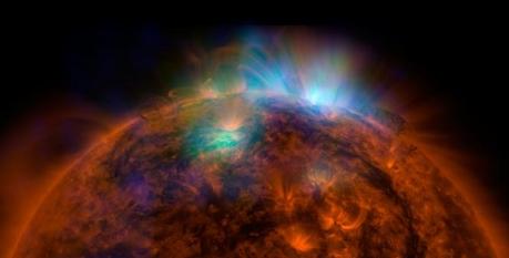 Alla ripresa del disco e della bassa atmosfera solare ottenuta dal Solar Dynamics Observatory della NASA nell’ultravioletto (in rosso-arancio) sono sovrapposte quelle di NuSTAR in verde e blu che ci svelano la radiazione di alta energia emessa dalla nostra stella.  Crediti: NASA/JPL-Caltech/GSFC