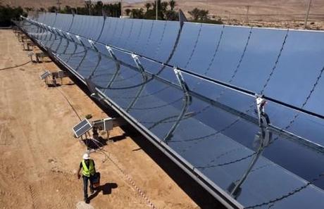 A worker walks next to parabolic mirrors at the research site of solar power company Brenmiller Energy near Dimona