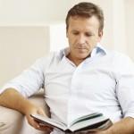 Handsome middle aged man reading a book at home