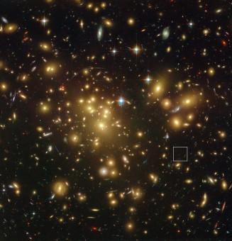L'immagine del telescopio spaziale Hubble della NASA/ESA mostra il ricco ammasso di galassie Abell 1689. L'enorme concentrazione di massa deflette la luce proveniente dagli oggetti più lontani e può aumentarne la luminosità apparente e renderle osservabili. Uno di questi oggetti, A1689-zD1, si trova all'interno del riquadro - anche se è ancora così debole che si vede appena in questa immagine. Crediti: NASA; ESA; L. Bradley (Johns Hopkins University); R. Bouwens (University of California, Santa Cruz); H. Ford (Johns Hopkins University); and G. Illingworth (University of California, Santa Cruz)
