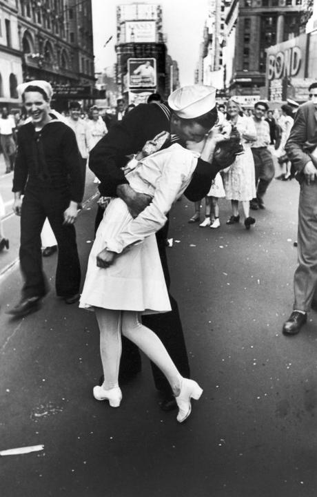 A jubilant American sailor clutching a white-unifo