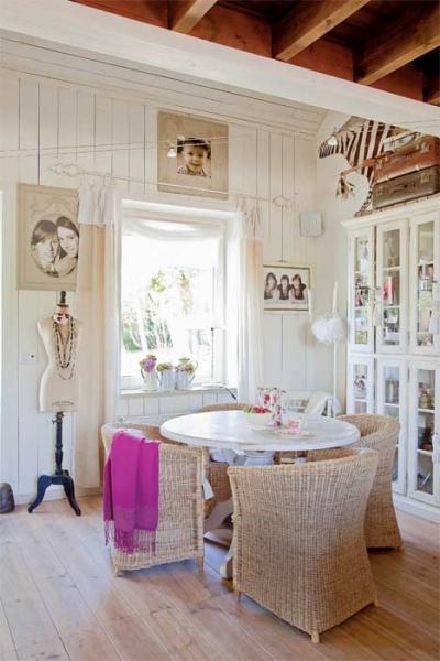 Ściany z pomalowaną na biało boazerią, stare kufry podróżne i wiklinowe fotele wprowadzają wakacyjny klimat. Ellen okrasiła dom kobiecymi dodatkami.