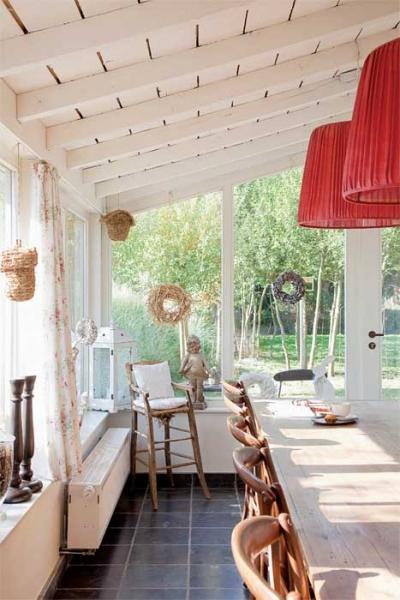 Goście i przyjaciele  spotykają się przy długim drewnianym stole w jadalni. Nadzwyczajnie wyglądają wielkie abażury z cienkiej czerwonej tkaniny.  