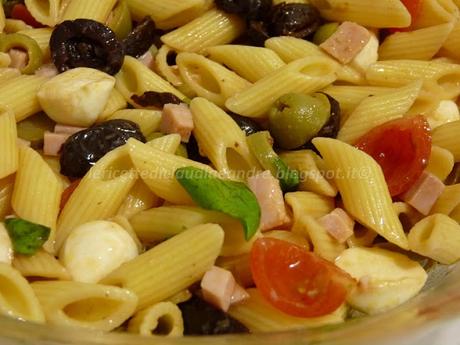 Insalata di pasta fredda con olive, pomodorini, prosciutto e mozzarelline